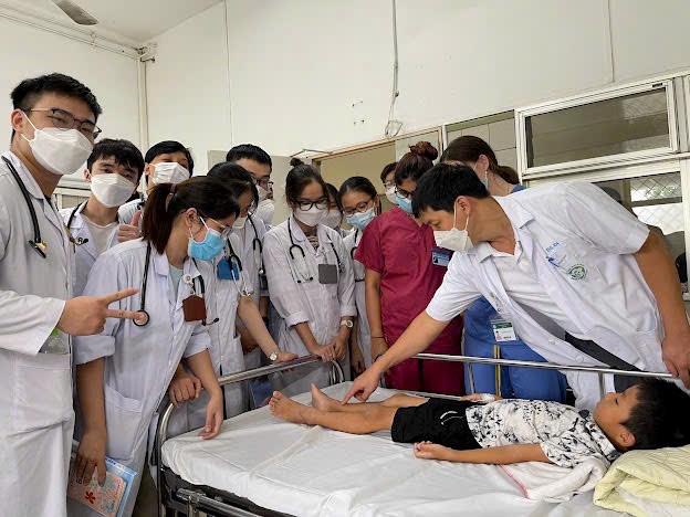 PGS.TS Phạm Văn Đếm, Phó Trưởng bộ môn Nhi, Trường Đại học Y Dược, ĐHQGHN đang hướng dẫn thực hành cho sinh viên kỹ thuật khám xuất huyết dưới da tại Trung tâm Nhi, Bệnh viện Bạch Mai
