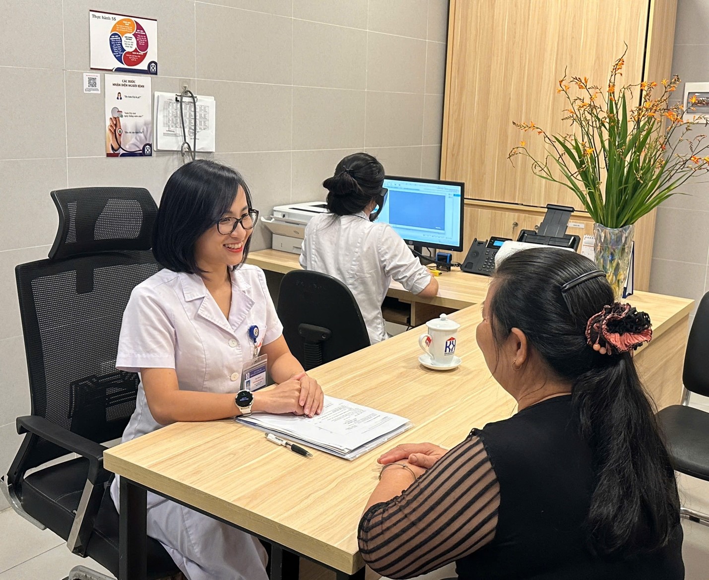 BSCKII Đinh Thị Hải Duyên trò chuyện với người bệnh đến thăm khám tại Bệnh viện Ung bướu Hà Nội.