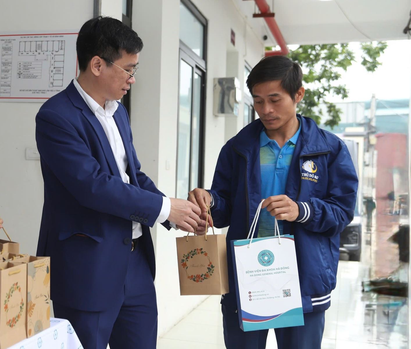 TS.BS Nguyễn Thành Vinh - Giám đốc BVĐK Hà Đông trao quà cho người dân đến khám trong ngày đầu vận hành mô hình phòng khám liên kết giữa BVĐK Hà Đông và Trạm Y tế xã Bình Minh.